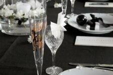 a black and white tablecape with floating flowers, a candle, black ornaments and white napkins