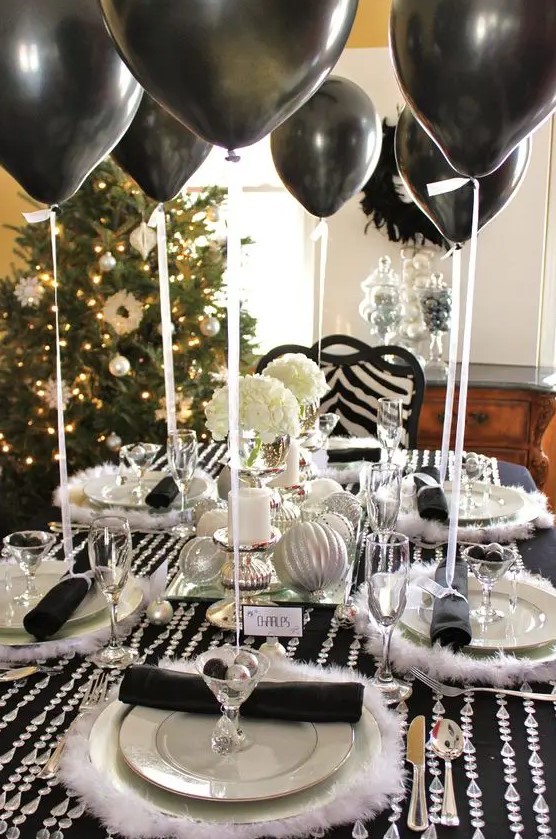 a black tablecloth, crystal garlands, faux fur placemats, black balloons and silver ornaments