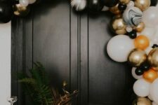 a black, white and gold balloon arch is a gorgeous NYE decoration, add ornaments in the same colors and enjoy