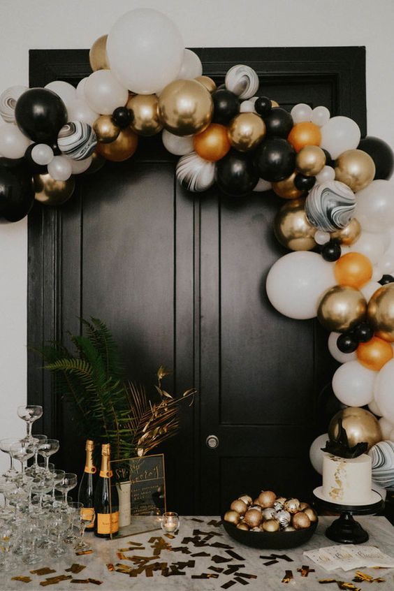 a black, white and gold balloon arch is a gorgeous NYE decoration, add ornaments in the same colors and enjoy