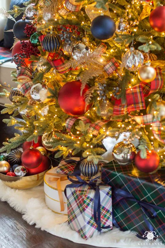 a bold and elegant Christmas tree with red plaid ribbon, navy, gold and red ornaments and gift boxes wrapped with plaid paper