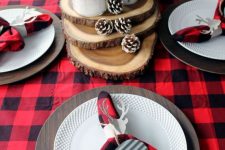 a bold and very simple Christmas tablescape with a plaid tablecloth and napkins, monogram napkin rings, slices, snowy pinecones and berries in jars