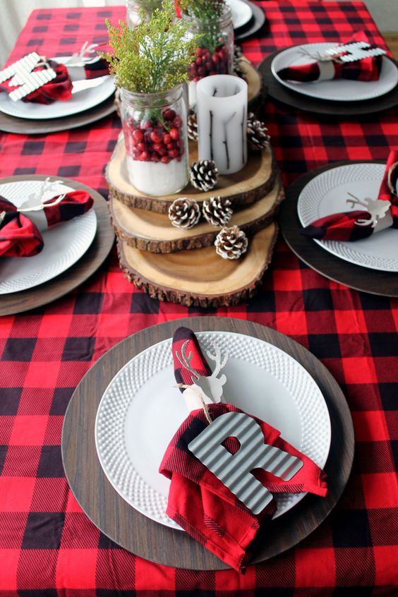 a bold and very simple Christmas tablescape with a plaid tablecloth and napkins, monogram napkin rings, slices, snowy pinecones and berries in jars