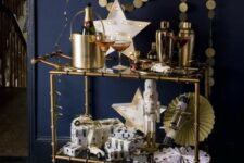 a brass NYE bar cart with a gold garland, a neon star sign, paper fans and a balloon