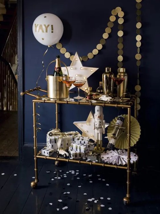 a brass NYE bar cart with a gold garland, a neon star sign, paper fans and a balloon