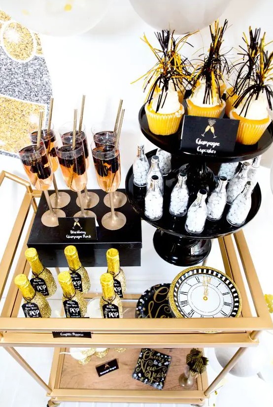 a brass bar cart with glitter bottles, fringe cupcake toppers and a glitter clock is a gorgeous idea for a NYE party