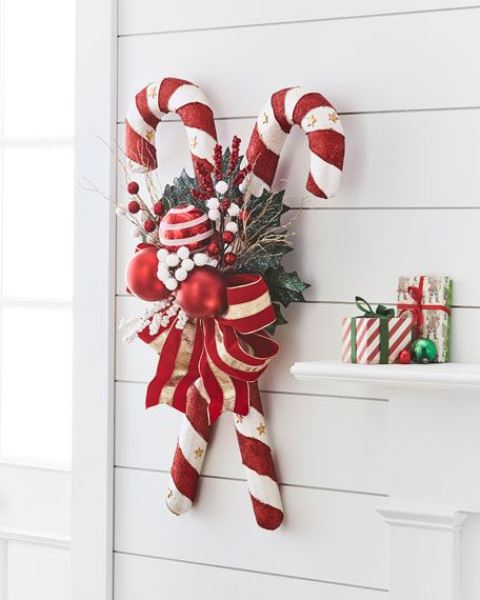 a bright Christmas decoration of oversized candy canes, foliage, berries, bright red and white ornaments and a large bow is lovely