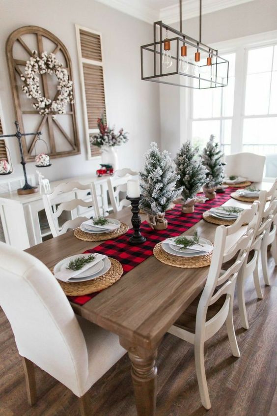 a bright and simple Christmas tablescape with a red plaid table runner, woven placemats, flocked Christmas trees and candles