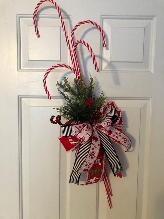 a bright door decoration of fir branches, bright bows and candy canes can be made in some minutes and looks fun and cool