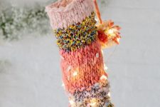 a bright knit Christmas stocking with pompoms and lights integrated is a cool and bold modern decoration for holidays
