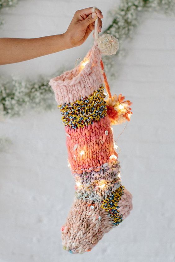 a bright knit Christmas stocking with pompoms and lights integrated is a cool and bold modern decoration for holidays