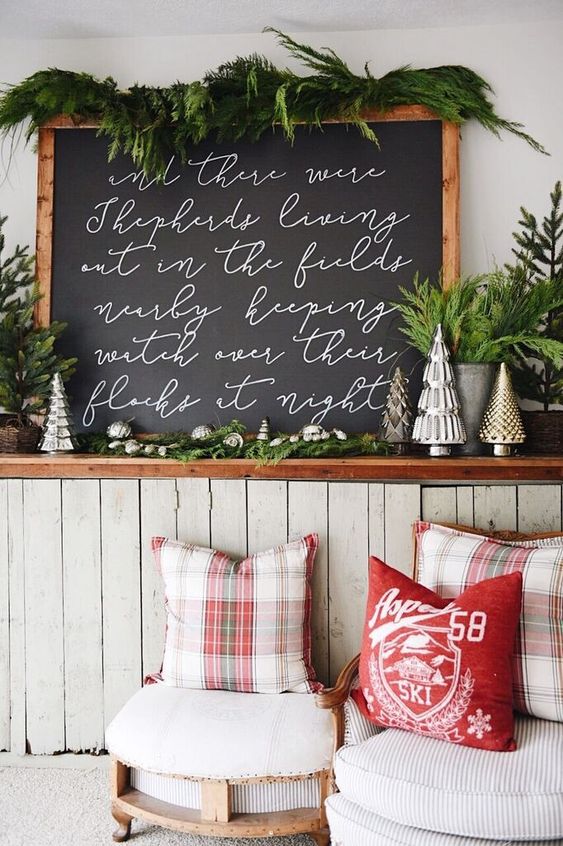 a chalkboard Christmas sign with white calligraphy and evergreens on top is a lovely idea