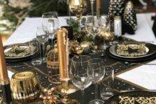 a chic black and gold NYE party tablescape with black table runners and placemats, black and gold plates, gold candles and candleholders