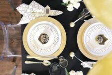 a chic black and gold tablescape with polka dots, geo prints and some white blooms