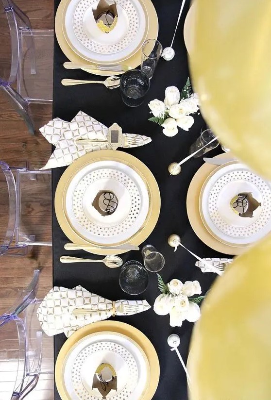 a chic black and gold tablescape with polka dots, geo prints and some white blooms