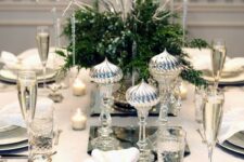 a chic silver-infused table setting with greenery and berries and silver imitating icicles and silver cutlery and chargers