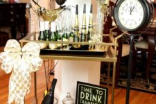 a classic black and gold NYE bar cart with black and gold balloons, a polka dot bow and some bottles and glasses