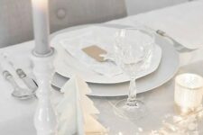 a clean white tablescape with a dove grey table runner, LEDs, stars, candles and wooden fir trees