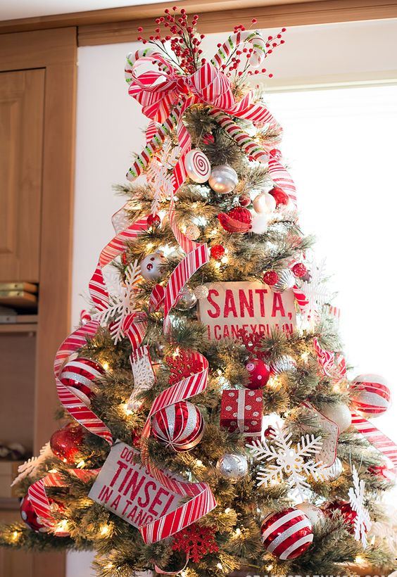 a colorful Christmas tree decorated with striped and silver ornaments, ribbons, candy ornaments and berries is fun