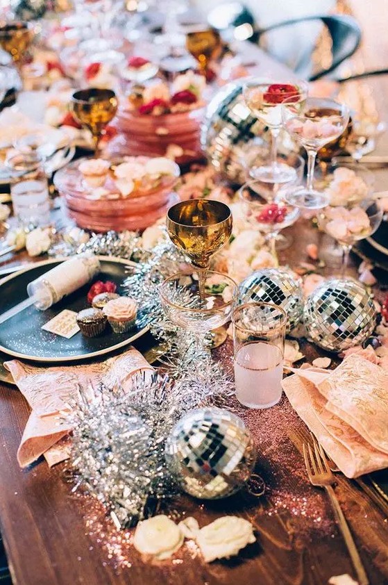 a colorful tablescape with disco balls, tinsel and gold cutlery for a sparkly New Year party