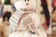 a creative snowman decoration of an old sweater, with a neutral scarf and a beanie is a cool decoration for both indoors and outdoors