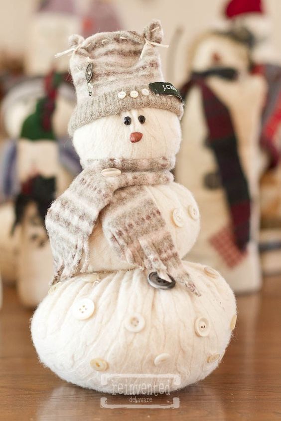 a creative snowman decoration of an old sweater, with a neutral scarf and a beanie is a cool decoration for both indoors and outdoors