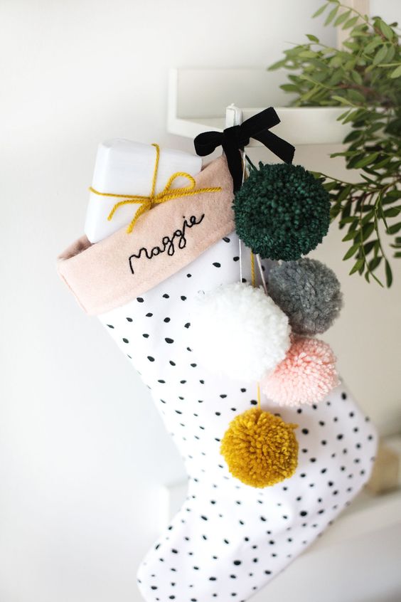 a cute polka dot stocking with muted color pompoms and gifts is a lovely decor idea for a girlish space