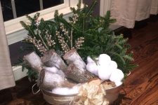 a galvanized bathtub with firewood, snowballs, fir branches, berries and a bow is a cool outdoor decoration for Christmas