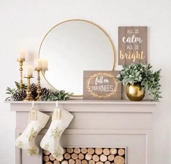 a glam and rustic Christmas mantel with large pinecones, gilded candle holders and a vase, a sign and a mirror