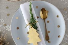 a gold and white Christmas tablescape with a lace runner, gold stars and polka dots, gold cutlery and ornaments