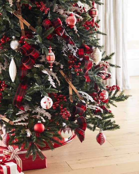 a gorgeous Christmas tree decorated with skis, red and white ornaments, plaid ribbons, berries and with red and white gifts under it