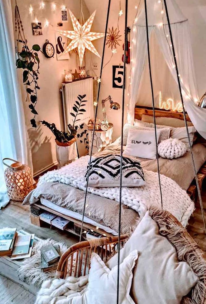 a gorgeous boho bedroom with a pallet bed with neutral bedding and blankets, nightstands with table lamps, a pendant chait, star shaped string lights over the bed
