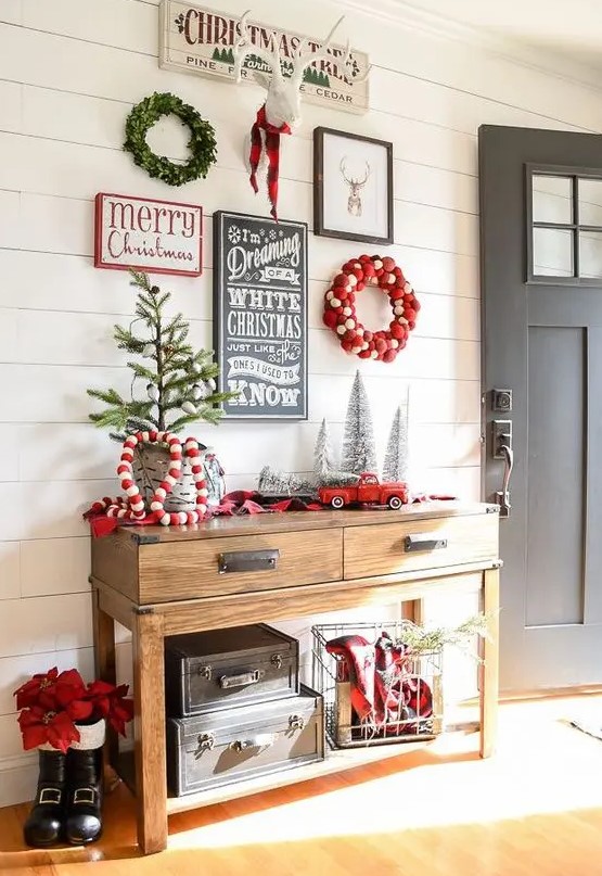 a gorgeous gallery wall for holidays with a couple of wreaths, signs and a fake deer head for your entryway