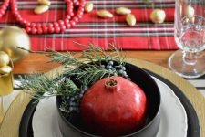a gorgeous plaid Christmas tablescape with plaid linens, gold nuts and ornaments, red beads and a pomegranate in a bowl