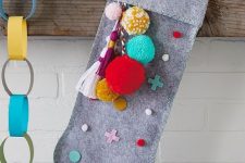 a grey felt stocking with colorful detailing – polka dots, crosses and pompoms and tassels is a lovely DIY piece for a modern space