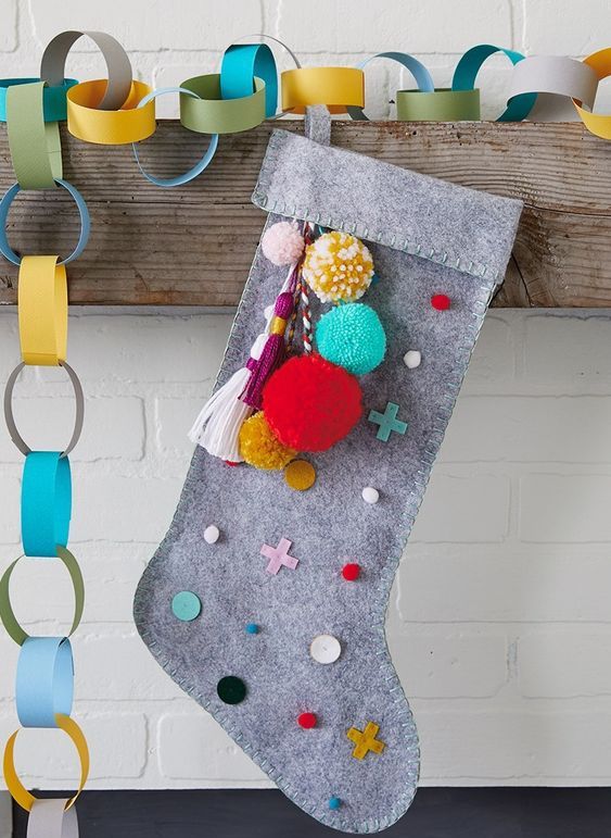 a grey felt stocking with colorful detailing - polka dots, crosses and pompoms and tassels is a lovely DIY piece for a modern space