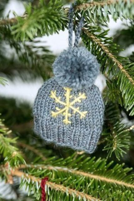 a grey knit beanie with a tine snowflake and a pompom is a pretty Christmas ornament that looks very winter-like