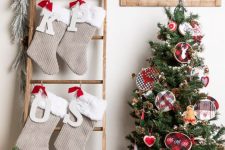 a ladder with tan and white faux fur Christmas stockings, monograms and evergreens is a cool alternative to a mantel with stockings