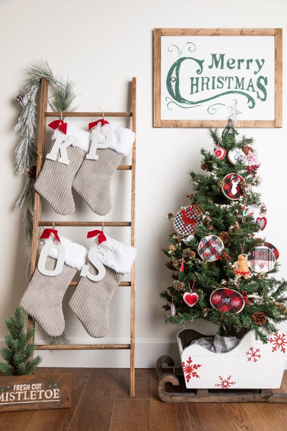 a ladder with tan and white faux fur Christmas stockings, monograms and evergreens is a cool alternative to a mantel with stockings