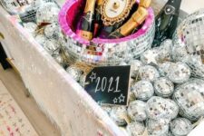 a large sink filled with disco balls and with champagne bottles placed here looks super glam, fun and bold, perfect for a NYE party