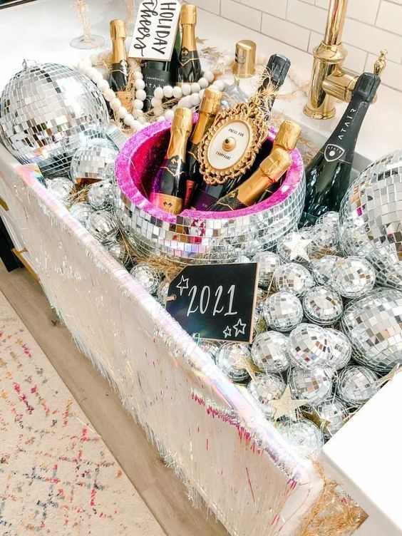 a large sink filled with disco balls and with champagne bottles placed here looks super glam, fun and bold, perfect for a NYE party