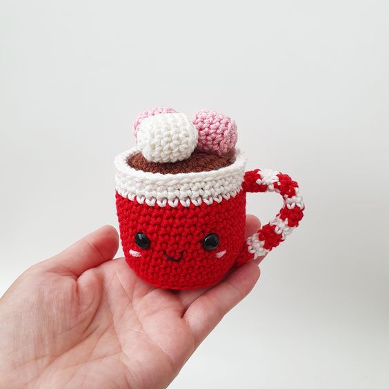 a little red and white knit mug with marshmallows on top is a cute Christmas ornament or decoration you can DIY