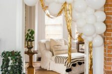 a lovely and modern NYE party decoration – an arrangement of white balloons with gold tinsel is a cool decor idea