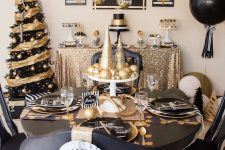 a modern and bold black and gold Christmas decor with a bright tree, balloons, hanging ornaments and a chic tablescape with printed placemats