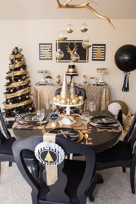 a modern and bold black and gold Christmas decor with a bright tree, balloons, hanging ornaments and a chic tablescape with printed placemats