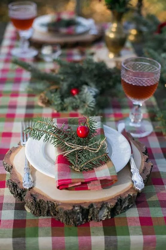 a plaid tablecloth, plaid napkins and evergreens with berries for a cozy rustic tablescape will create a festive feel at your Christmas table