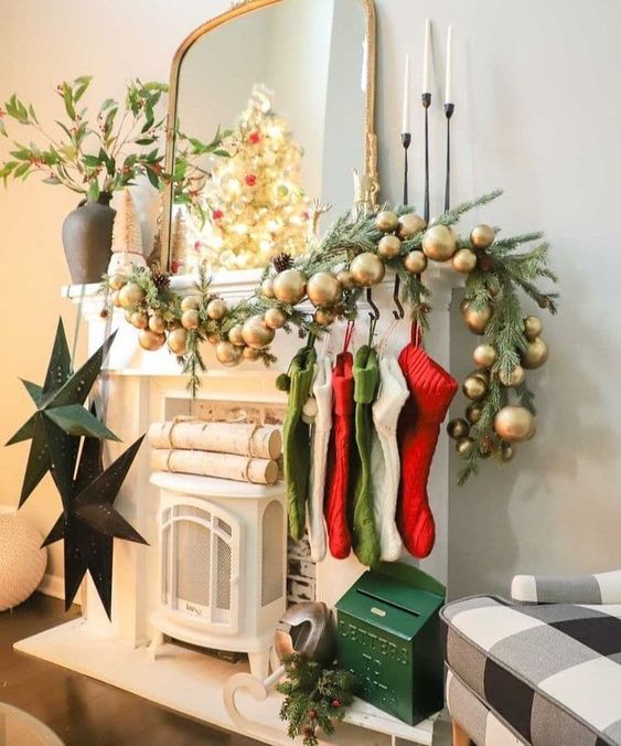 a pretty Christmas mantel in traditional colors, with an evergreen and gold ornament garland, red, green and white stockings