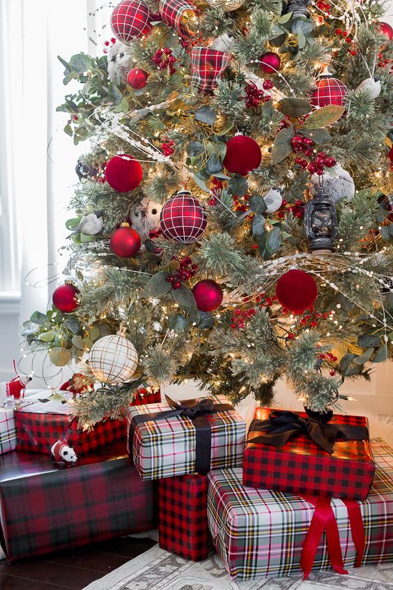 a pretty and bold Christmas tree decorated with glossy red, red velvet, red plaid ornaments and greenery plus matching gift boxes under the tree