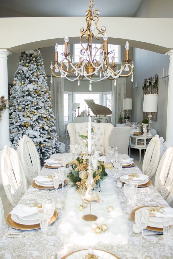 a pretty and bright Christmas tablescape with gold ornaments, leaves, chargers and cutlery, tall and thin candles