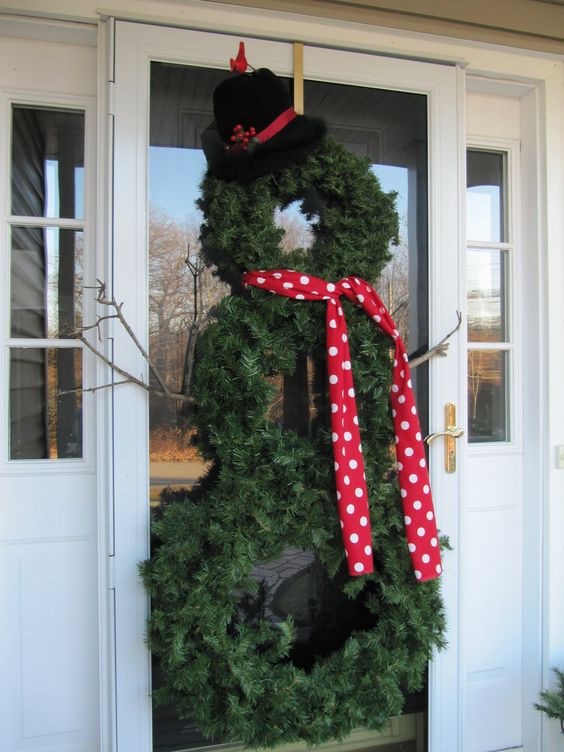 a pretty evergreen snowman made of wreaths, with a polka dot scarf, a black hat and some branch hands is a cool idea